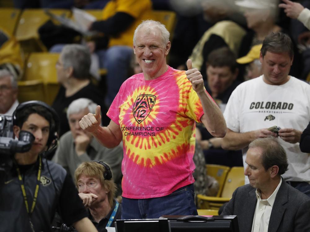 Television announcer and retired NBA star Bill Walton, center, smiles as he takes his seat courtside to provide commentary in the first half of an NCAA college basketball game between Oregon and Colorado, on Jan. 28, 2017, in Boulder, Colo.