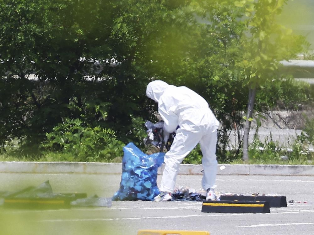 An officer wearing protective gear collects the trash from a balloon presumably sent by North Korea, in Siheung, South Korea, on Sunday.