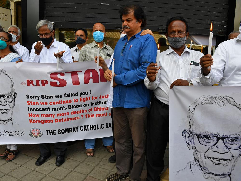 People hold posters and candles outside a Mumbai church holding a memorial mass for the Indian rights activist and Jesuit priest Father Stan Swamy on July 6, 2021. Swamy was detained for nine months without trial under Indian anti-terrorism laws, and died on July 5, 2021 ahead of a bail hearing, officials said.