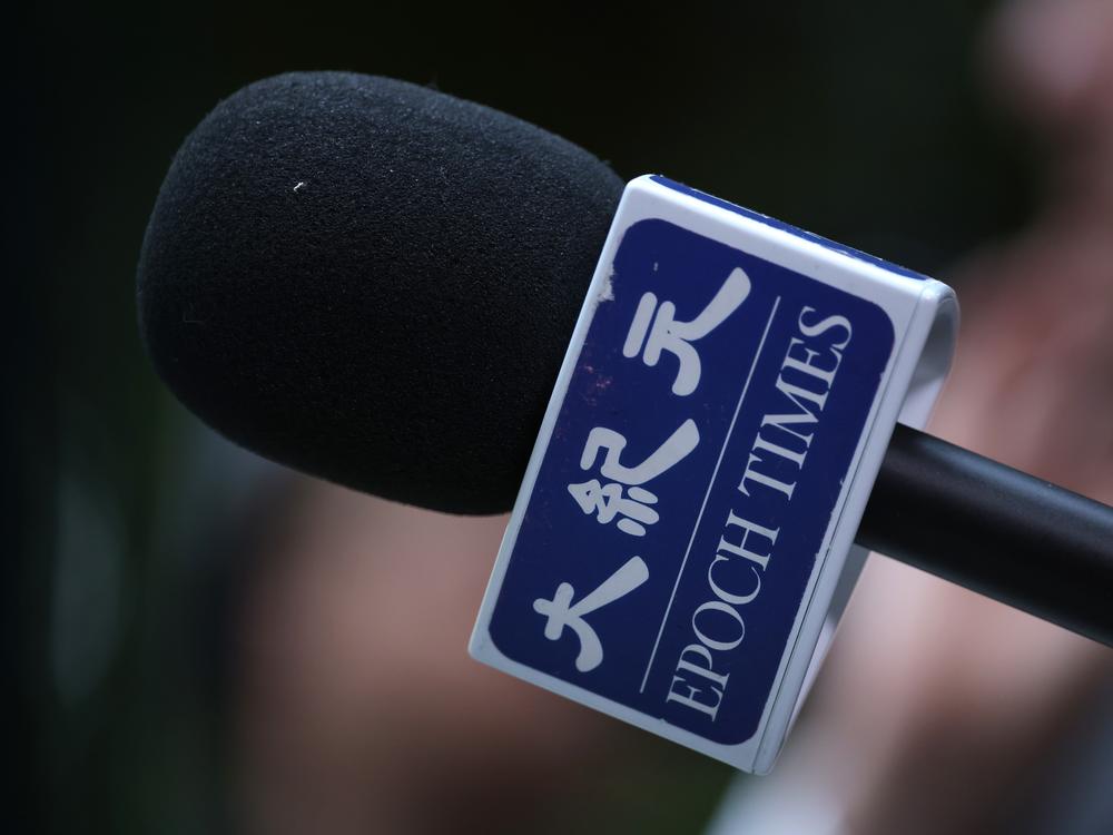 A reporter for The Epoch Times holds a microphone during a media event on Oct. 23, 2023, in Berlin, Germany. The Epoch Times is owned by Epoch Media Group and is affiliated with the Falun Gong movement.