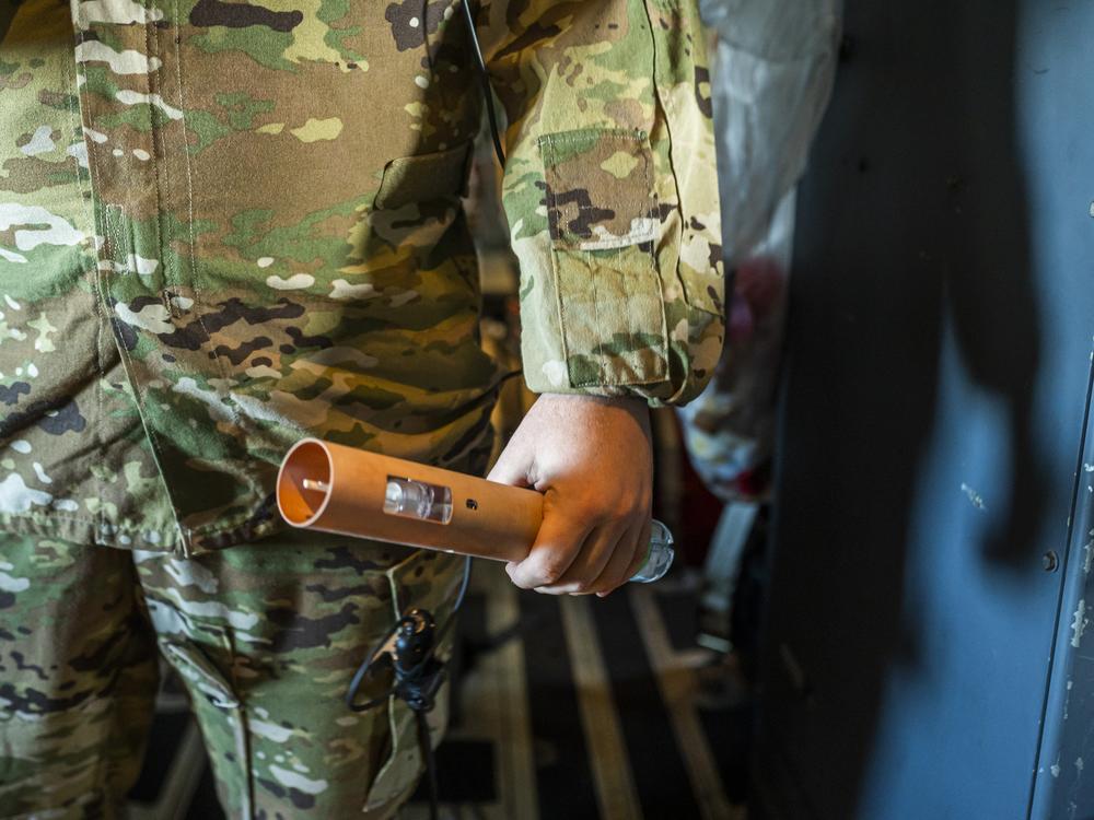 Staff Sergeant Donny Arseneaux gets ready to deploy a dropsonde from the belly of the plane. It takes readings in a hurricane, tracking wind speed and direction, temperature, humidity, and atmospheric pressure.