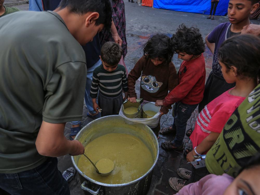 Palestinian children who took refuge in Quds school wait in line to receive food distributed by charity organizations for their families in Rafah, Gaza on April 01, 2024.
