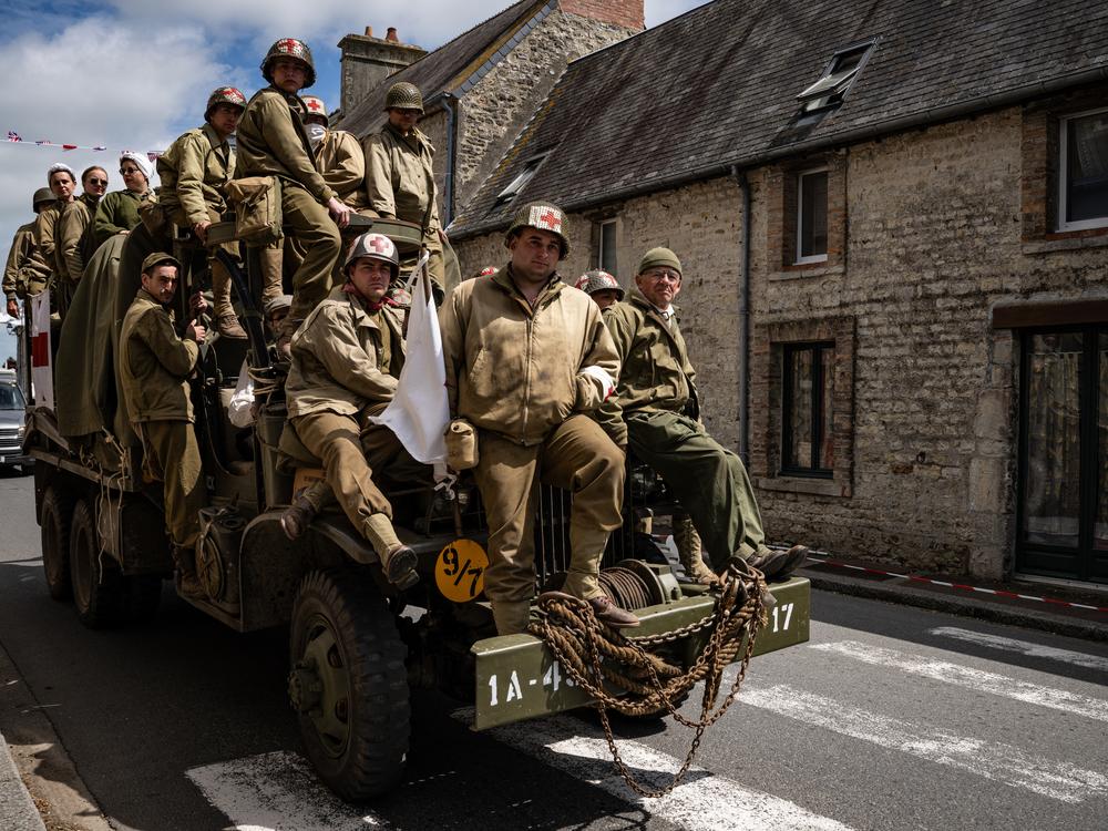 Enthusiasts wearing replica World War II military attire ride atop a WWII-era military truck in Saint-Côme-du-Mont, northwestern France, on Tuesday, as part of the D-Day commemorations marking the 80th anniversary of the World War II Allied landings in Normandy. The D-Day ceremonies on June 6 this year mark the 80th anniversary.