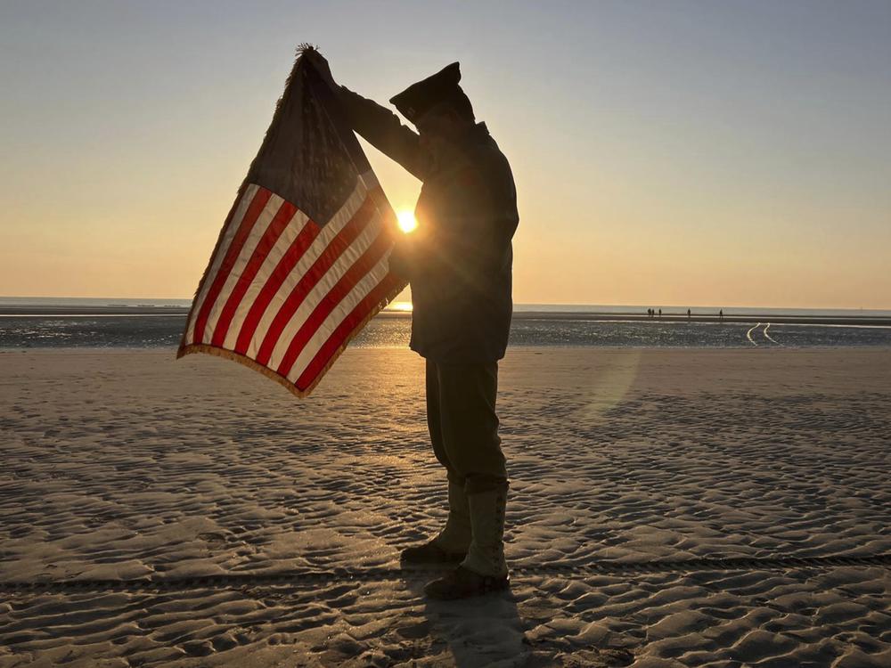 Christophe Receveur, of France, unfurls an American flag he bought six months ago in Gettysburg, Pa., to mark D-Day on Thursday on Utah Beach, Normandy. 