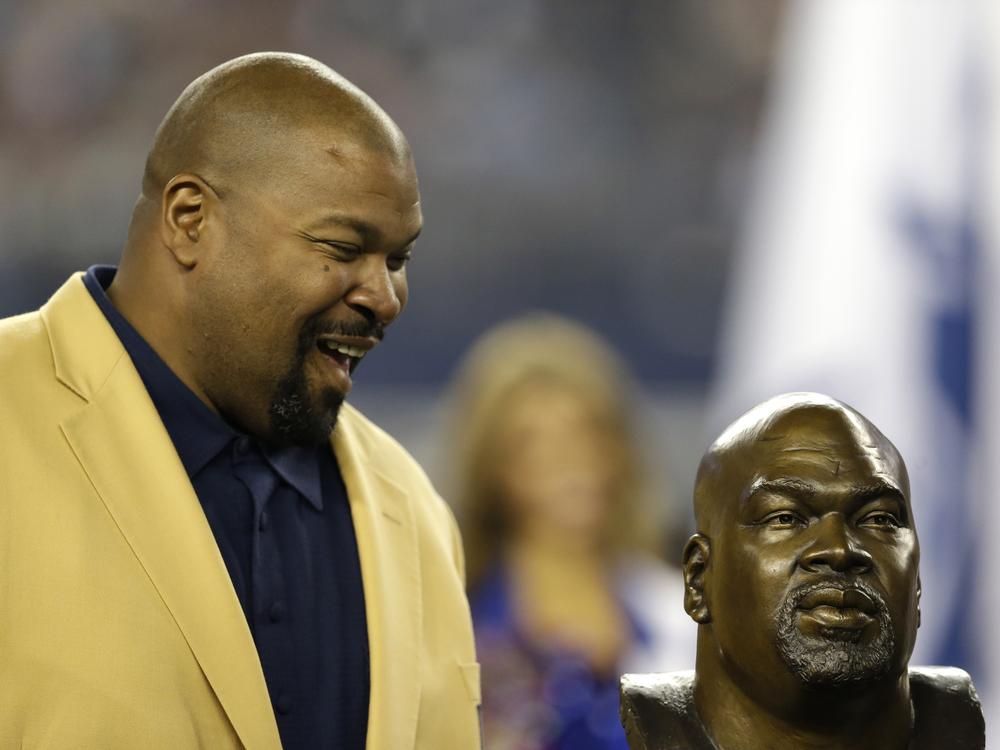 Former Dallas Cowboys player and Hall of Fame player Larry Allen looks down at a bust of himself as Allen is honored at halftime of an NFL football game against Washington on Oct. 13, 2013, in Arlington, Texas. 
