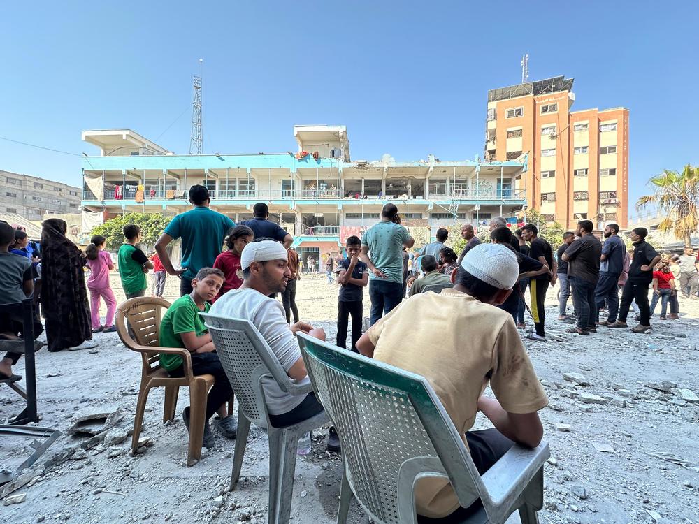 Injured men sit outside the scene of destruction caused by an Israeli strike on a U.N. school in Nuseirat in central Gaza.