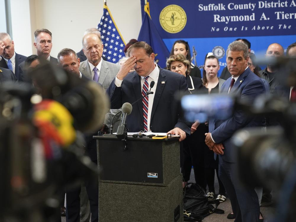 Surrounded by law enforcement, victims' families, attorneys and others, Suffolk County District Attorney Raymond Tierney pauses during a news conference in Riverhead, N.Y., on Thursday.
