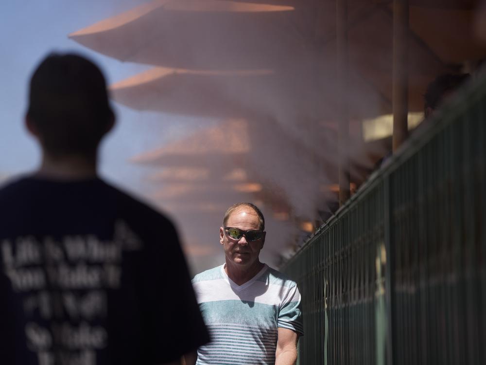 People walk through cooling misters on June 4, 2024 in Las Vegas. Tens of millions of people from California to Texas are experiencing intense heat. New data shows that the amount of planet-warming carbon dioxide in the atmosphere has hit a new record.