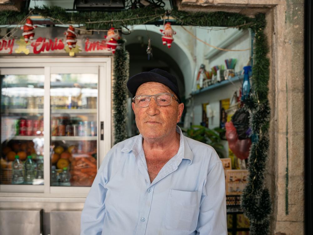 Rimon Himo, 69, a Palestinian resident of the Old City of Jerusalem, stands in front of his shop after being attacked by a mob. 