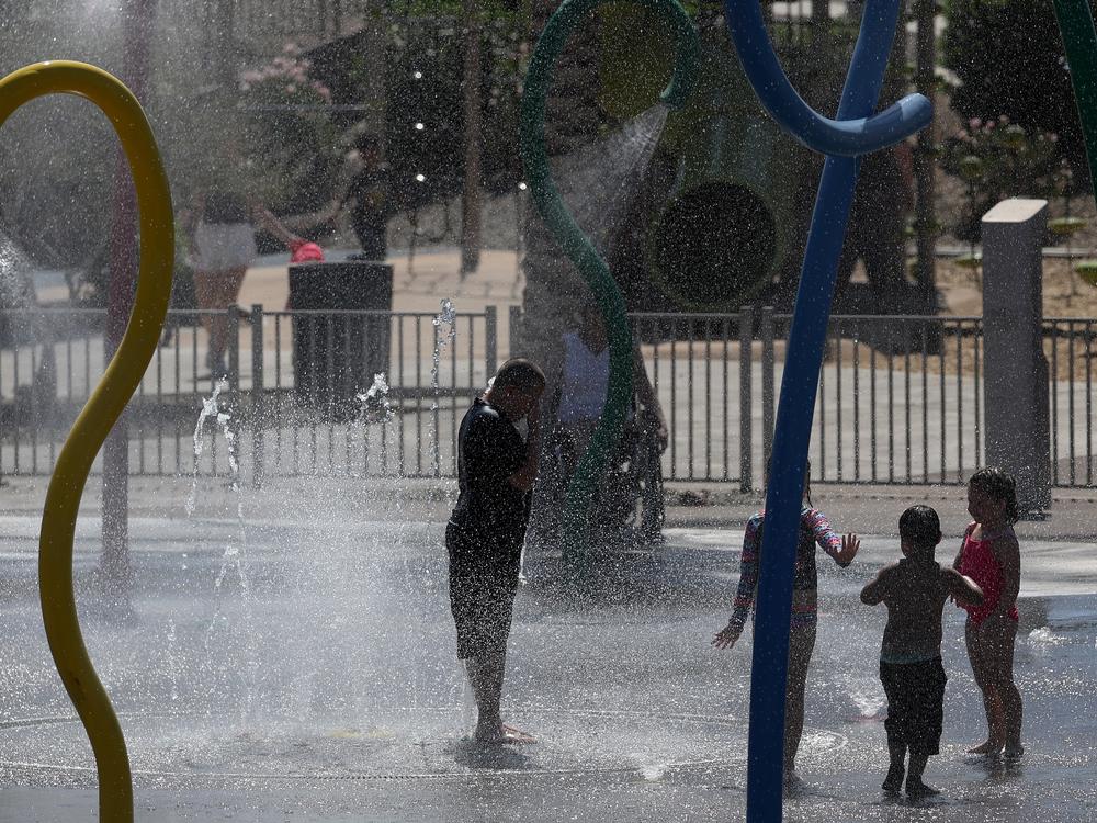 Kids play in a splash pad at Riverview Park on Wednesday in Mesa, Ariz. Experts warn to make sure any outdoor play time includes plenty of water and shade — and breaks from the heat — during an extended heat wave. 