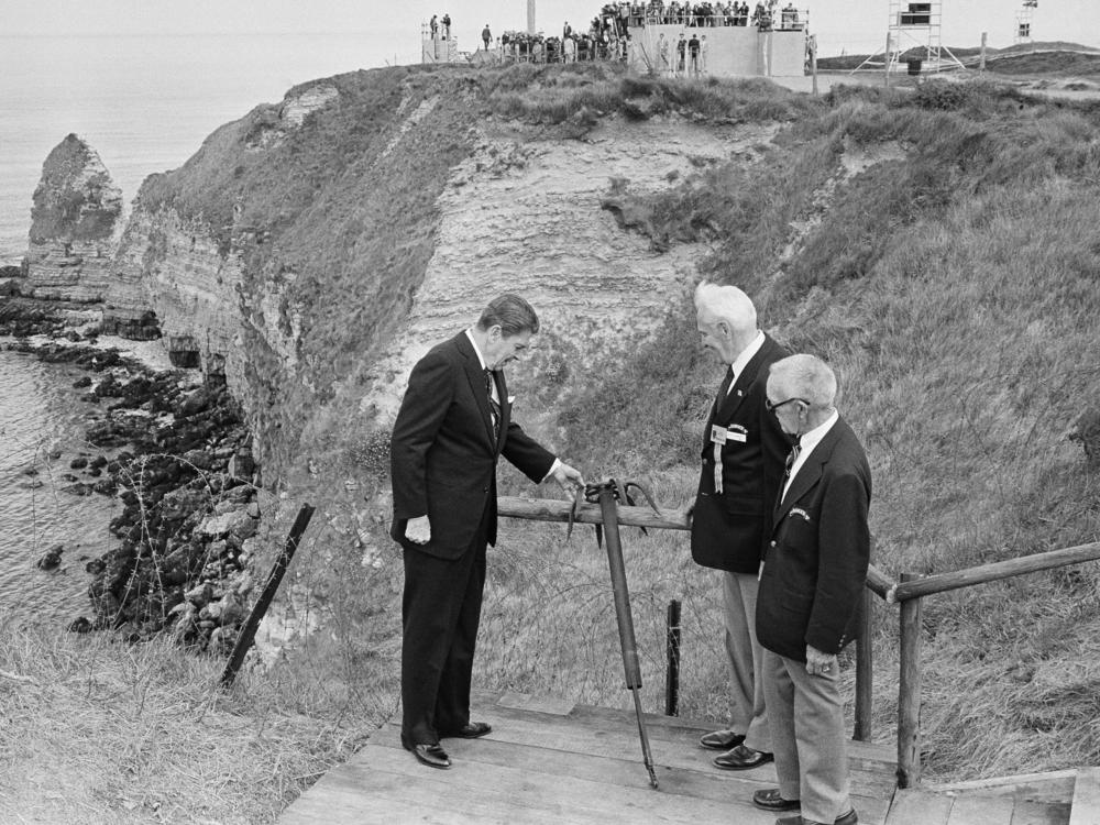 President Ronald Reagan and two veterans look at a hook used by the U.S. Army Rangers to climb the cliffs of Pointe du Hoc during commemorations for the 40th anniversary of D-Day on June 6, 1984.