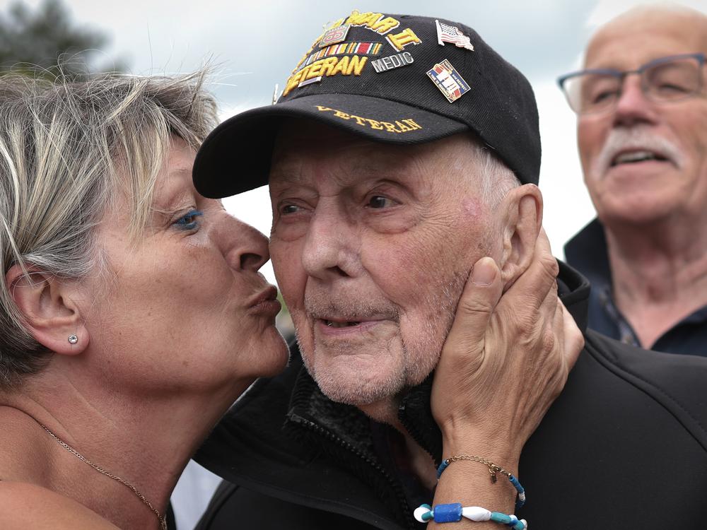 World War II veteran Gene Kleindl, age 102, from Rockford, Ill., receives a kiss from Chantell Boivin while leaving the Normandy American Cemetery on June 4 in Colleville-sur-Mer, France. Kleindl, a medic in the U.S. Army's 90th Infantry Division, arrived on the beaches of Normandy on D-Day.