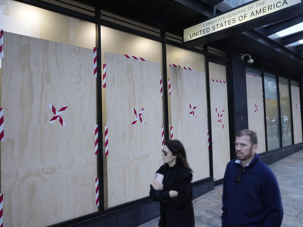 A couple walks past the boarded windows at the U.S. consulate as police investigate the vandalism in Sydney on Monday.