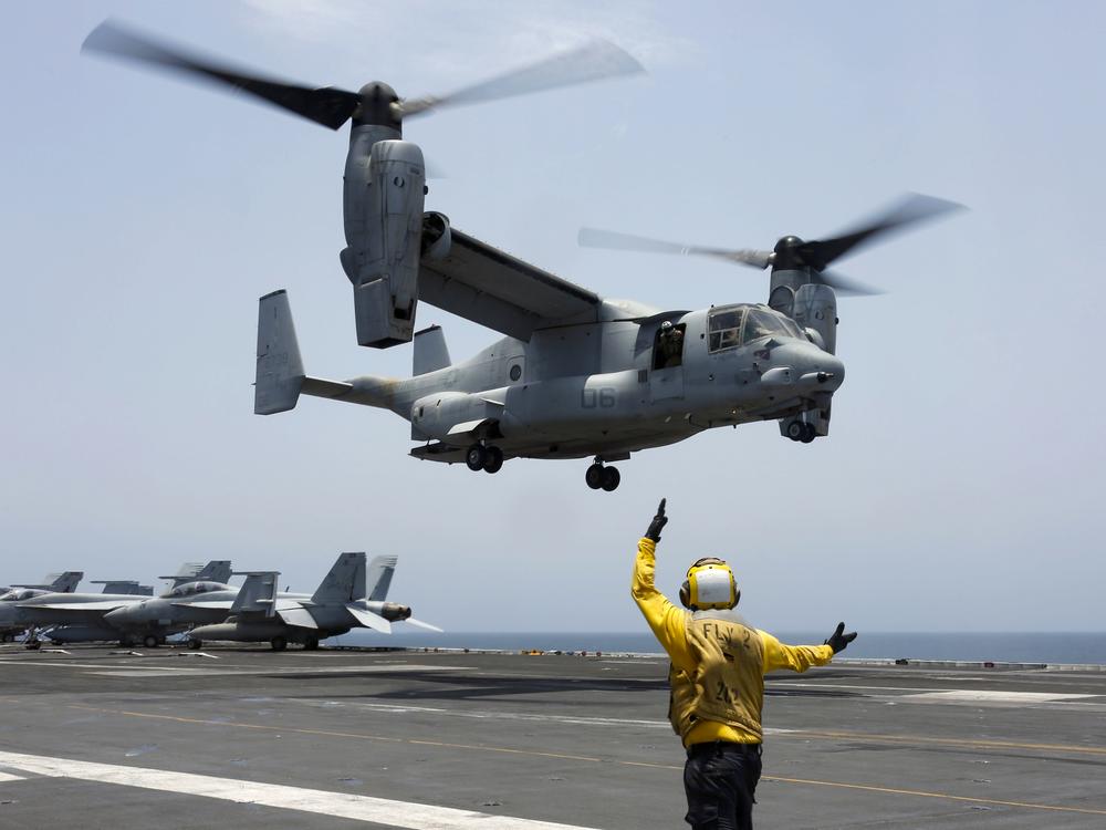 In this image provided by the U.S. Navy, a crew member signals an MV-22 Osprey to land on the flight deck of the USS Abraham Lincoln in the Arabian Sea in 2019.