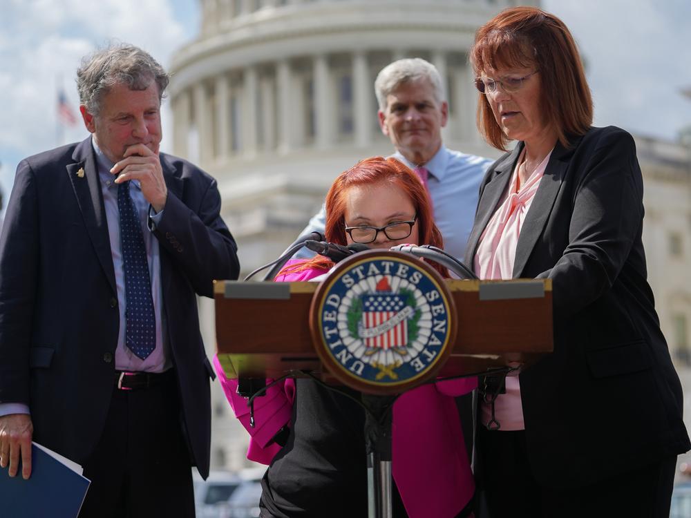 Democratic Sen. Sherrod Brown of Ohio (left) and Republican Sen. Bill Cassidy of Louisiana (in back) listen to Emily Demko and her mother, Margaret Demko, outside the U.S. Capitol last summer during a press conference on reforming the SSI program.
