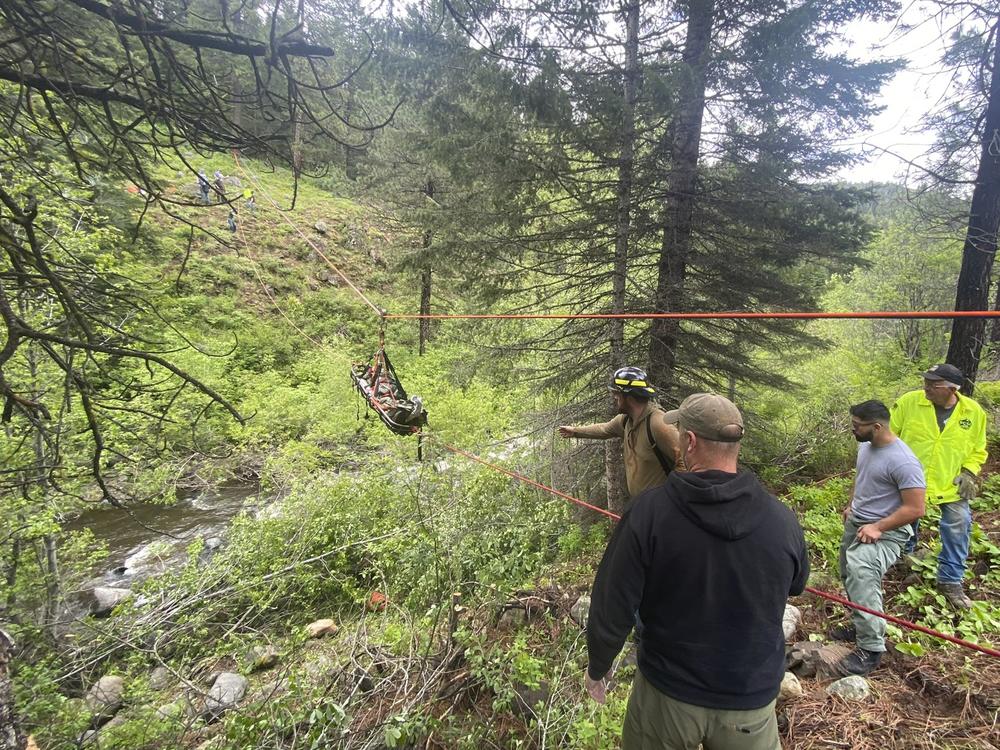 In this image provided by the Baker County Sheriff's Office, responders aid in rescue efforts after a vehicle went into an embankment on U.S. Forest Service Road 39 on June 3, 2024, in Oregon. A dog helped his owner get rescued after the crash by traveling nearly four miles to the campsite where the man was staying with family, which alerted them that something was wrong, authorities said.  