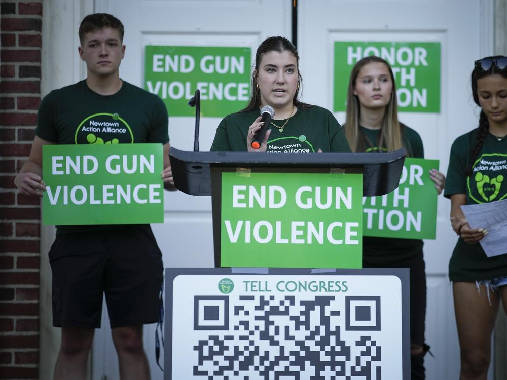 Emma Ehrens, center, a survivor of the Sandy Hook Elementary School shooting, speaks as she stands with other survivors during a rally against gun violence on Friday, June 7, 2024, in Newtown, Conn.