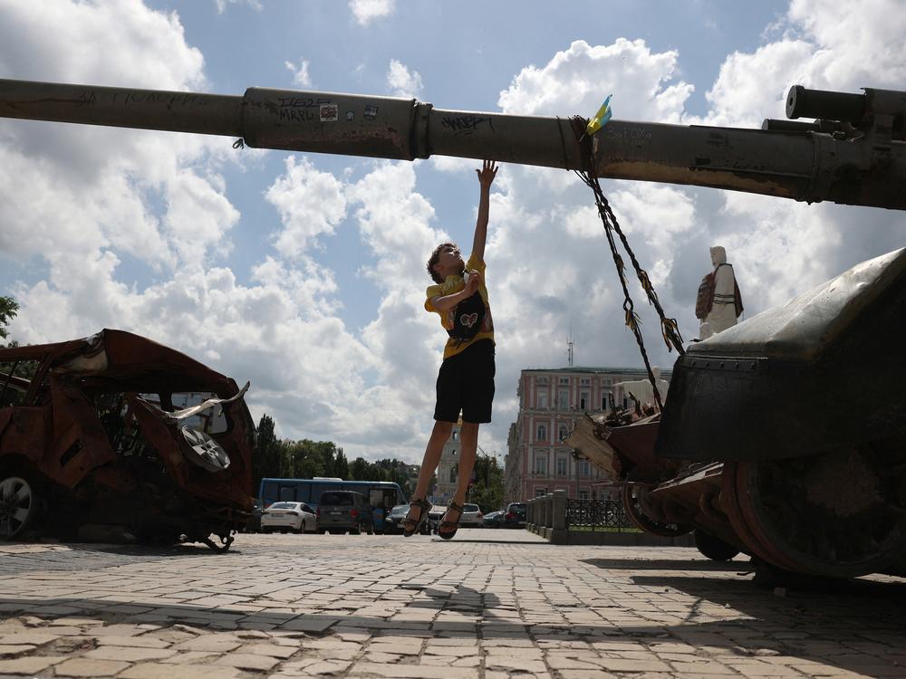 A boy jumps next to a destroyed Russian self-propelled gun on Mykhailivska Square in the center of Kyiv on June 11.