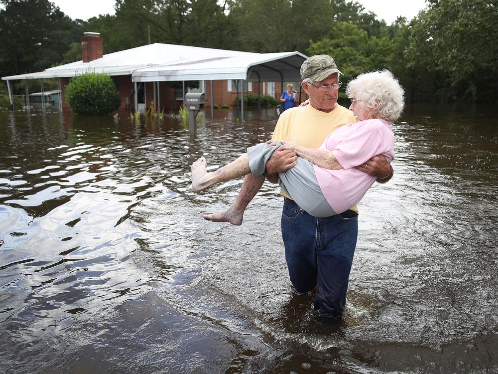 Bob Richling carries Iris Darden through floodwater from Hurricane Florence in September 2018 in Spring Lake, North Carolina. Counting hurricane-related deaths can be complicated because sustained power outages can contribute to fatalities for weeks or even months after the storm passes.