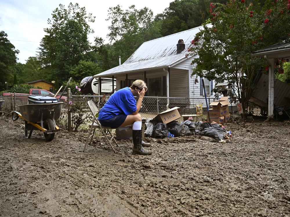 Teresa Reynolds sits exhausted as her neighbors remove debris from their flood-ravaged homes in Hindman, Ky., in July 2022. The deadly floods were caused by torrential rains. Climate change makes such record-breaking rainstorms more common in much of the United States.