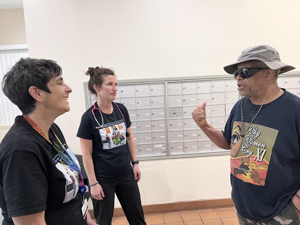 Nurses Lisa Stambolis and Ashley Gresh of the Neighborhood Nursing team talk with Percy Jones. Members of the nursing team visit his apartment building weekly, and Jones credits them with easing his worries about recovering from a hernia surgery when he couldn't get a timely appointment with his doctor. 