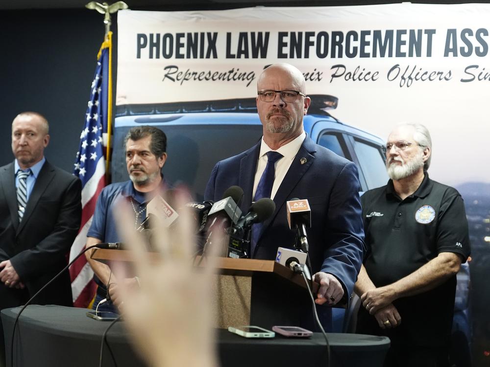 Darrell Kriplean, president of the Phoenix Law Enforcement Association, which represents about 2,200 Phoenix officers, stands at a lectern with microphones to take a question during a news conference Thursday in Phoenix. A Justice Department report said Phoenix police discriminate against Black, Hispanic and Native American people, unlawfully detain homeless people and use excessive force, including unjustified deadly force.
