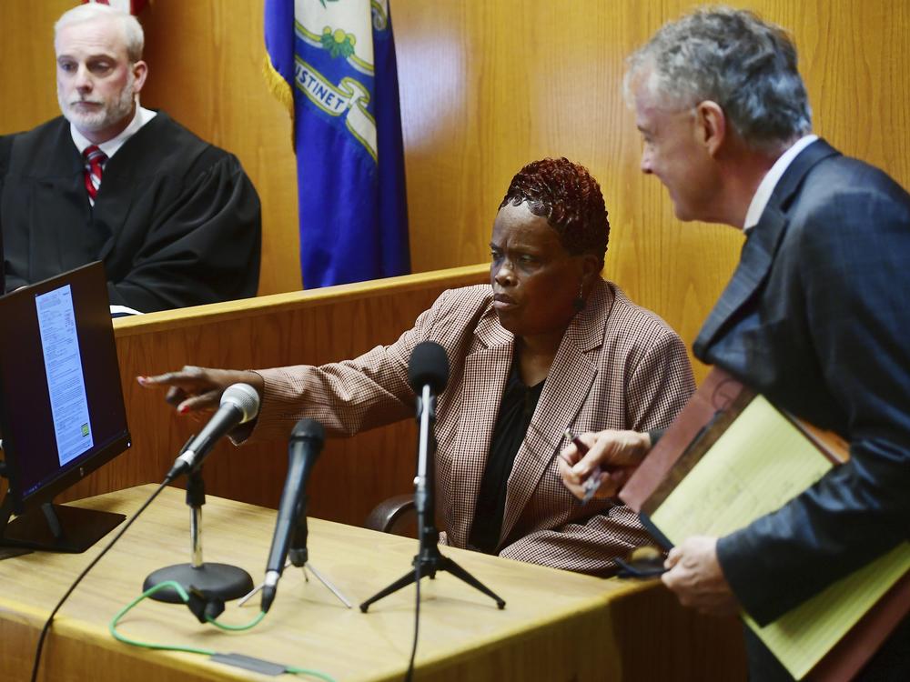 Wanda Geter-Pataky (center) talks with her lawyer, John Gulash (right), during October 2023 testimony in a challenge of absentee ballots in the 2023 Bridgeport, Conn., mayoral Democratic primary. Geter-Pataky was among four people charged Tuesday in relation to the city's 2019 mayoral primary.