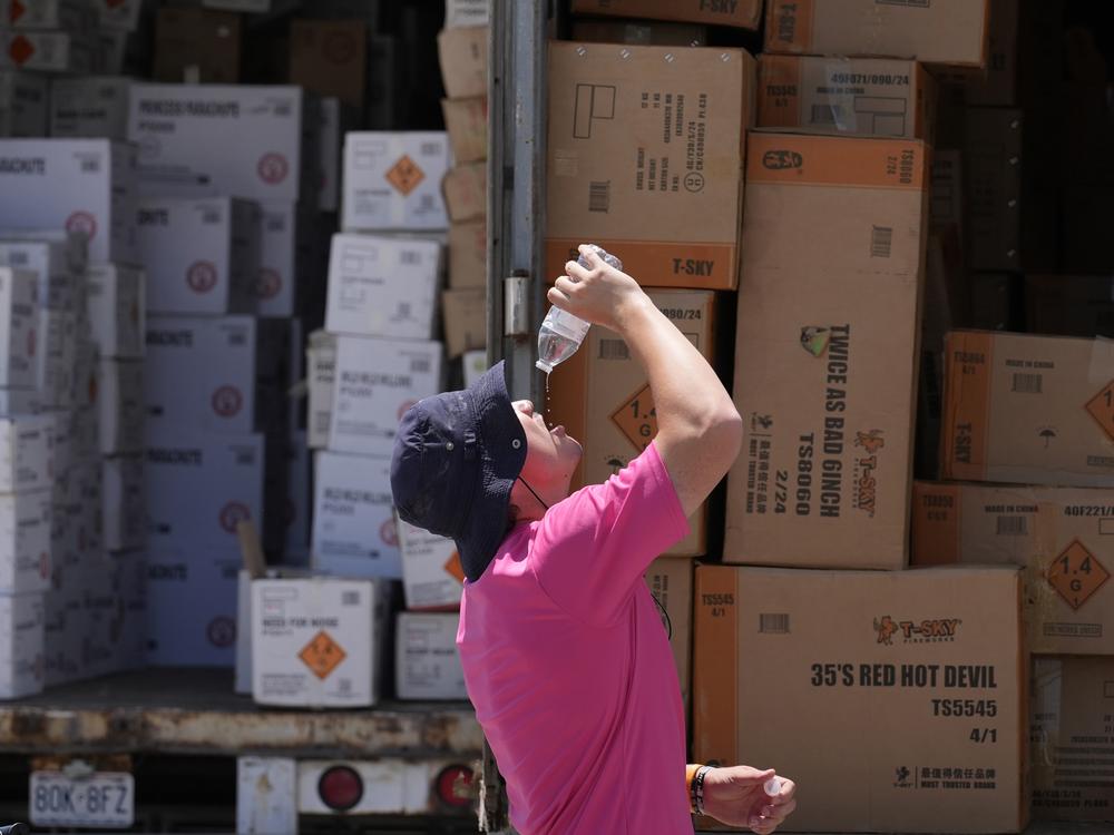 Wyatt Seymore pours the last drops of liquid from a water bottle into his mouth on June 17 as he takes a break from unloading a stiflingly hot trailer of fireworks outside Powder Monkey Fireworks ahead of the opening of the stand in Weldon Spring, Mo. 