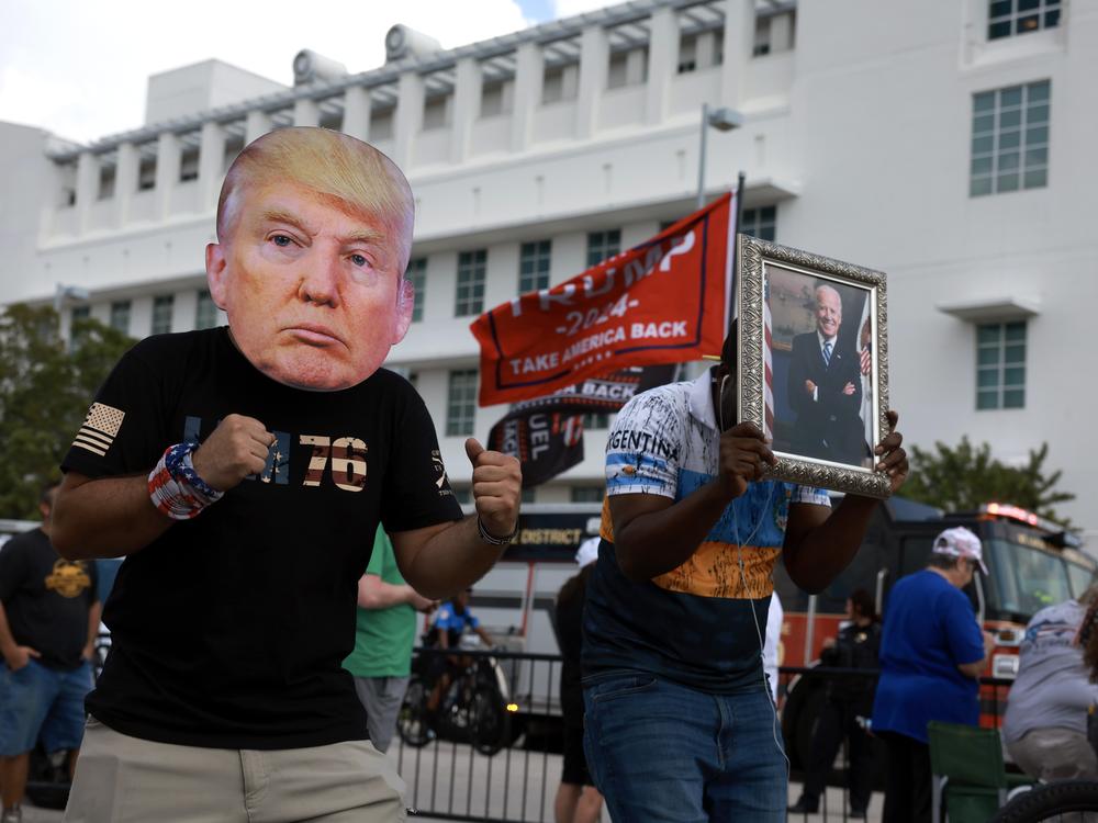 A man wears a mask of former President Donald Trump in front of a Fort Pierce, Fla., courthouse.