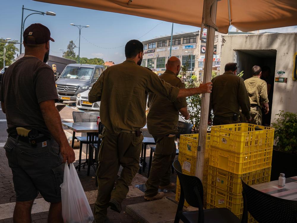 Soldiers and civilians enter a rocket shelter as sirens sound in the Israeli town of Kiryat Shmona on the Lebanese border on June 10.
