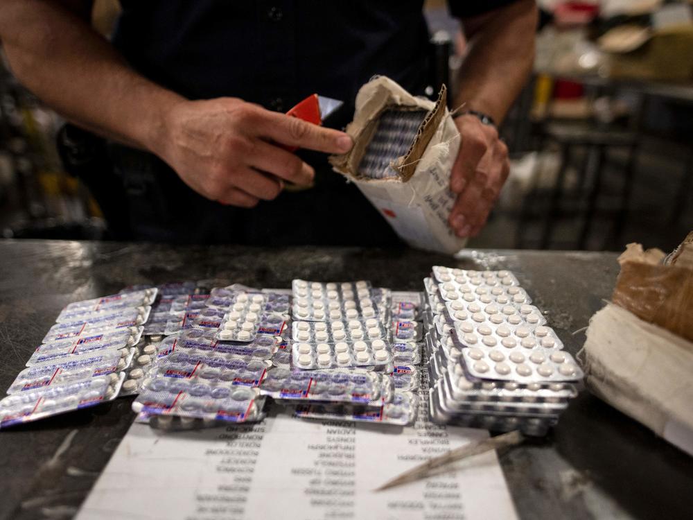 An officer from the U.S. Customs and Border Protection, Trade and Cargo Division finds Oxycodone pills in a parcel at John F. Kennedy Airport's US Postal Service facility on June 24, 2019, in New York. 