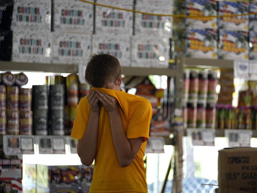 Hunter Van Dyne pauses to wipe sweat from his forehead inside a hot fireworks tent as he works to set up for the opening of Powder Monkey Fireworks, in Weldon Spring, Mo., on Monday.