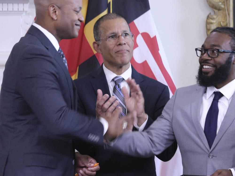 Shiloh Jordan, right, who was among the people receiving a pardon for a misdemeanor marijuana conviction years ago, greets Maryland Gov. Wes Moore at a news conference in Annapolis, Md., on June 17 when Moore announced more than 175,000 pardons. Maryland Attorney General Anthony Brown is center. 