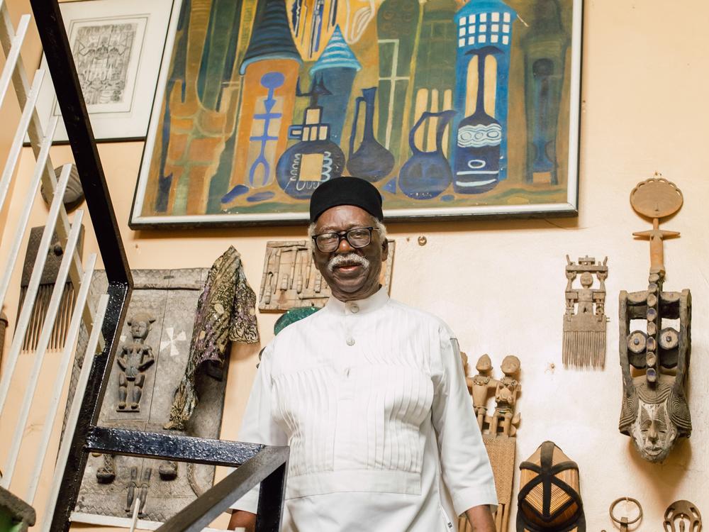 Artist Bruce Onobrakpeya stands before a wall of his artworks at his home studio in Lagos. The studio fills two floors of his three-story residence.
