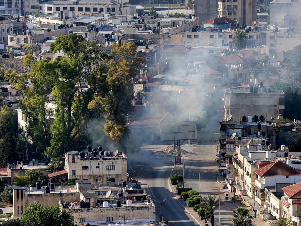 A cloud of smoke billows during an Israeli army raid in Jenin in the occupied West Bank on June 6. The Israeli military said it was investigating an incident in which a wounded Palestinian man was strapped to an Israeli military jeep while forces carried out 