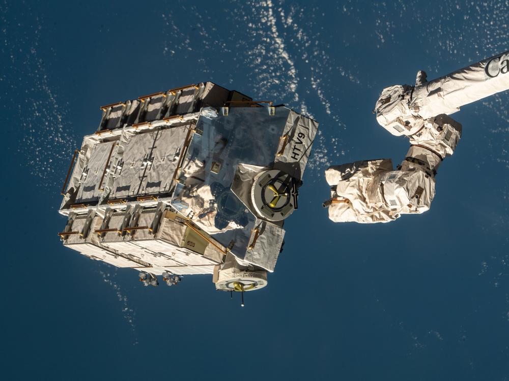 A robotic arm at the International Space Station is seen releasing a pallet packed with batteries in 2021. NASA says a metal alloy stanchion from that flight equipment is what landed in a Florida home.