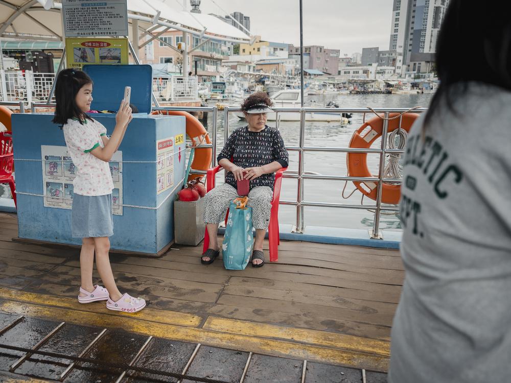 Kim Yong-jae, 82, sits as she rides the Gaetbae ferry while visitors take photos around her in Sokcho, South Korea, on Sept. 17, 2023.