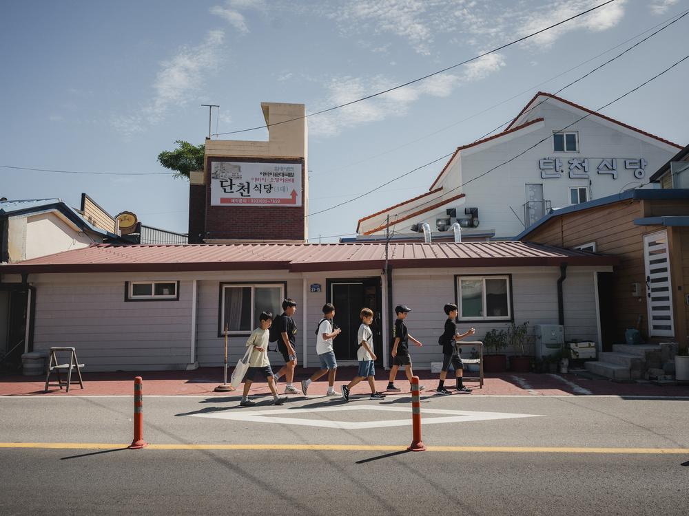 School children walk around Abai Village on Sept. 10, 2023. The village is now a tourist destination due to its history of being a village of displaced people from North Korea. Only a few dozen displaced people remain.