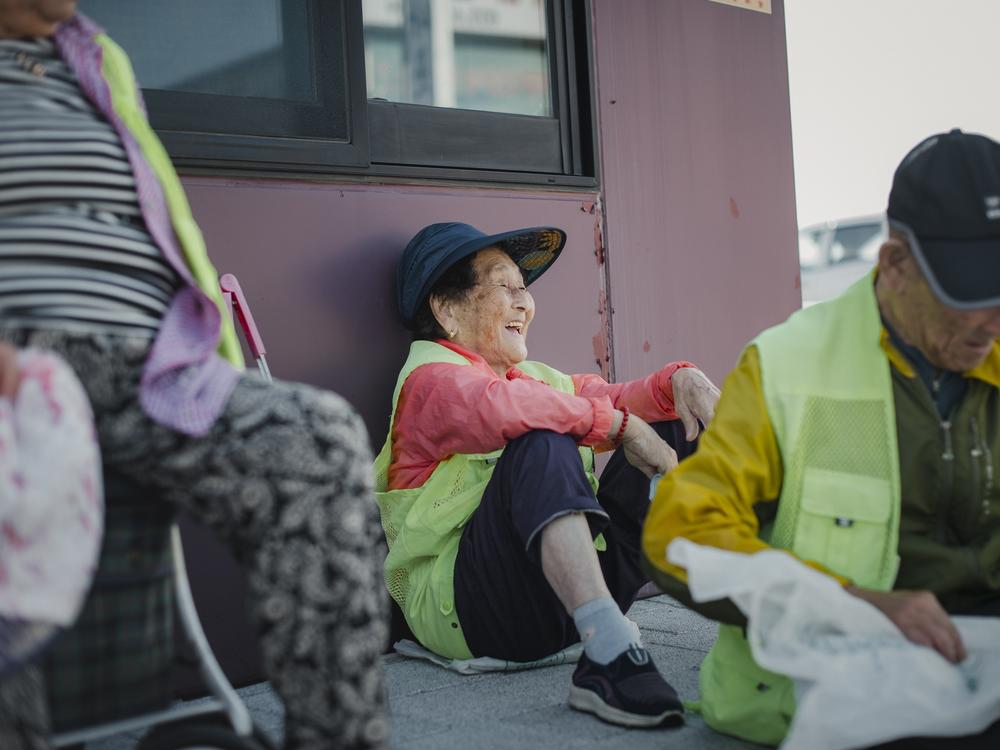 Friends Lee Hwa-ja, Jun Sook-ja (center) and Choi Gi-hwal rest after picking up garbage around Abai Village in Sokcho, South Korea, on Sept. 12, 2023. 