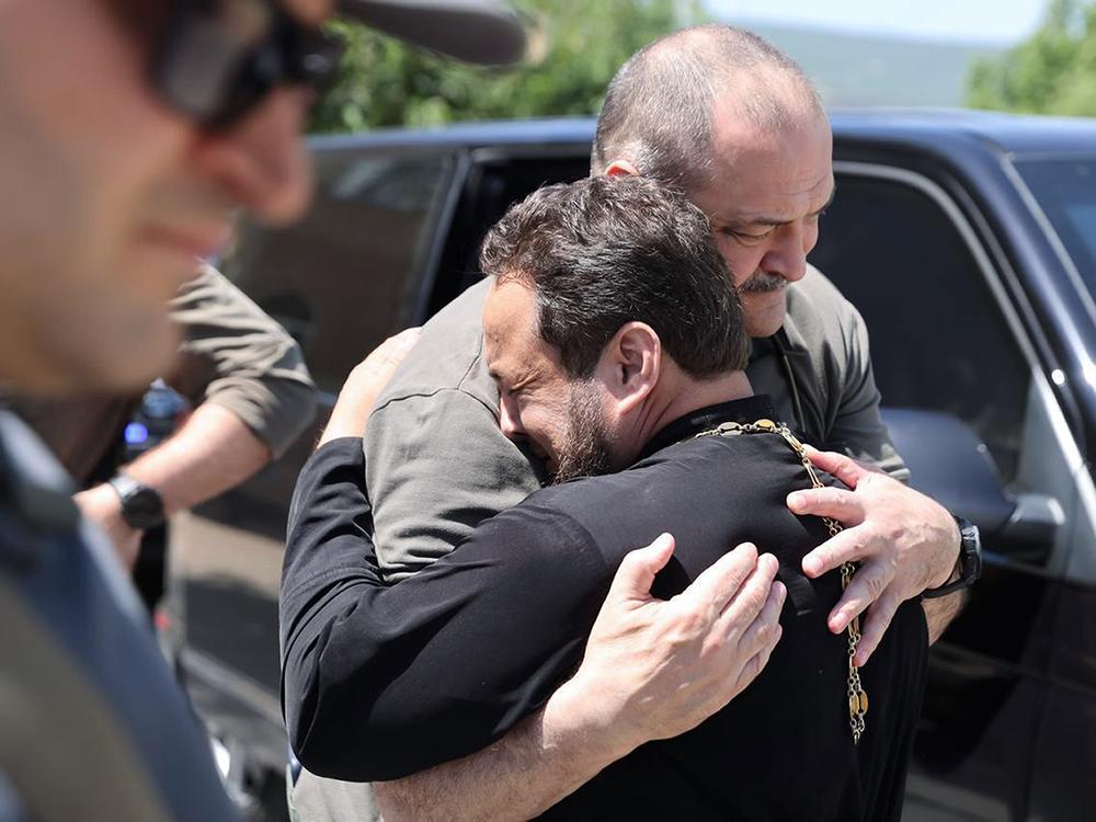 In this photo released by the Telegram channel of the administration of the head of Dagestan Republic of Russia on Monday, the head of Dagestan Republic, Sergei Melikov (center), embraces and comforts a priest as he visits an Orthodox church in Derbent after a counterterrorism operation.