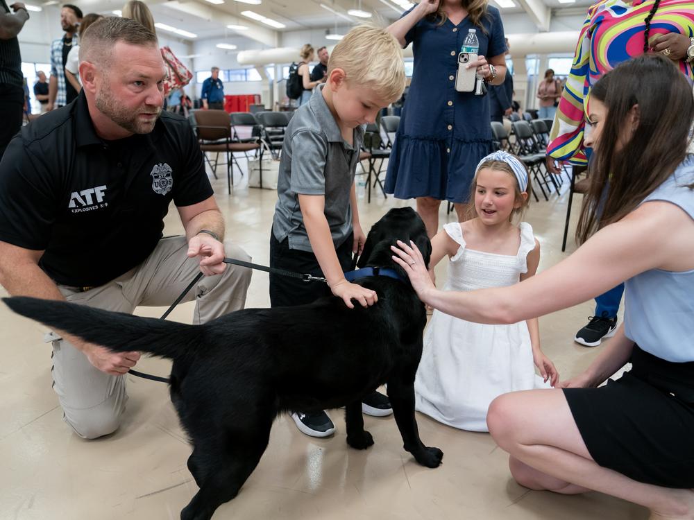 Special Agent Corey Wells introduces his K-9 Tara to his children, Owen Wells, 5, and Lucy Wells, 9, following a graduation ceremony for Bureau of Alcohol, Tobacco, Firearms and Explosives (ATF) special agent canine handlers and their dogs at the ATF training facility in Front Royal, Va., on Friday, June 21, 2024. 