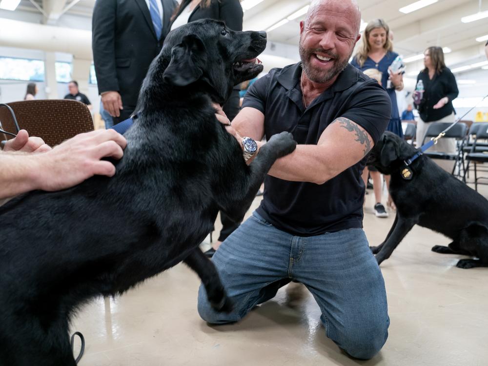 Carl Roth, a senior instructor with Puppies Behind Bars, greets K-9 Tara, who he worked with before her training, during a graduation ceremony for Bureau of Alcohol, Tobacco, Firearms and Explosives (ATF) special agent canine handlers and their dogs at the ATF training facility in Front Royal, Va., on Friday, June 21, 2024.