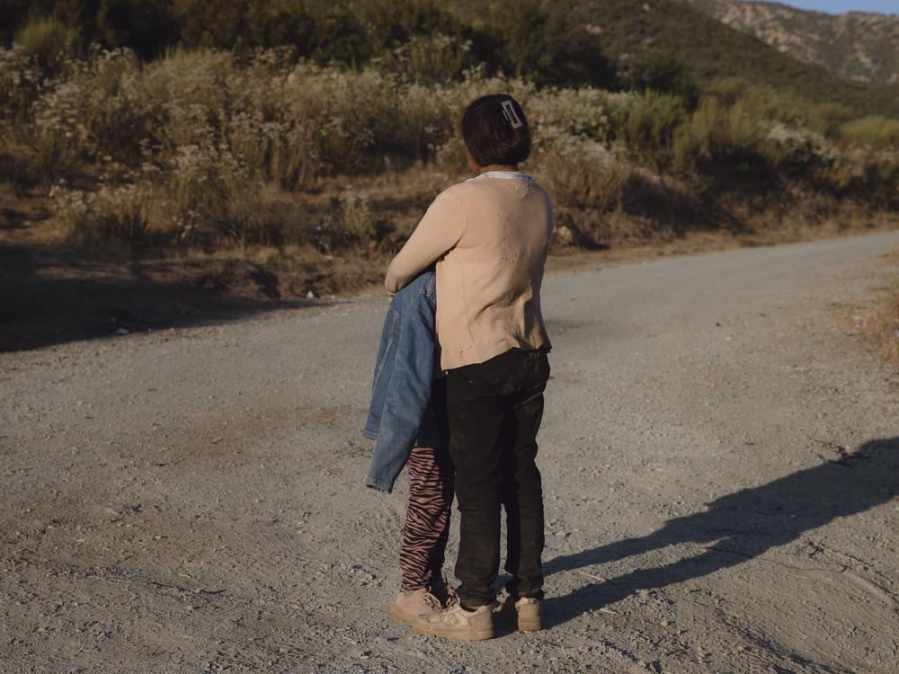 A migrant woman and her nine-year-old hold each other as they wait for border patrol agents in Dulzara, California. The family of three migrated from Ecuador and is hoping to seek asylum in the U.S. June 25, 2024. 