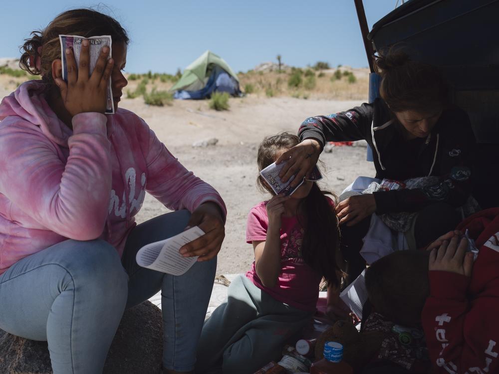 Jazmin Mora puts a cold patch on her forehead to cool down as she and her family wait for border patrol agents in Jacumba Hot Springs, California on June 24, 2024.  
