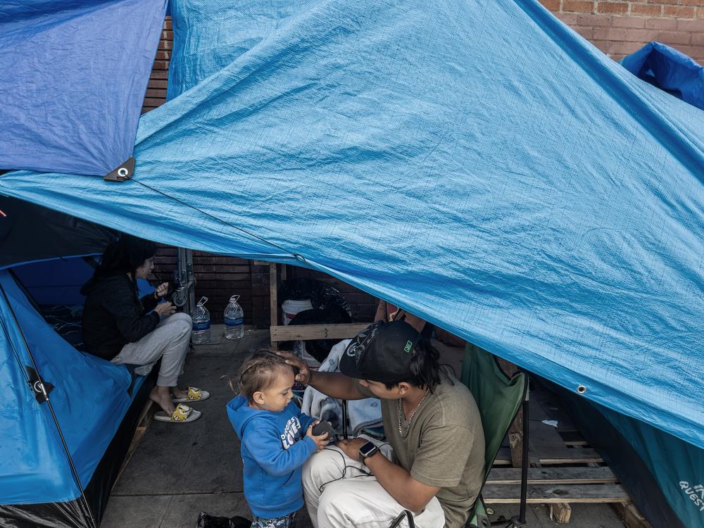 A homeless family with a two-year-old child on Towne Avenue in Los Angeles' Skid Row in April 2024. A new study tracks how housing insecurity affects children's health over time. 