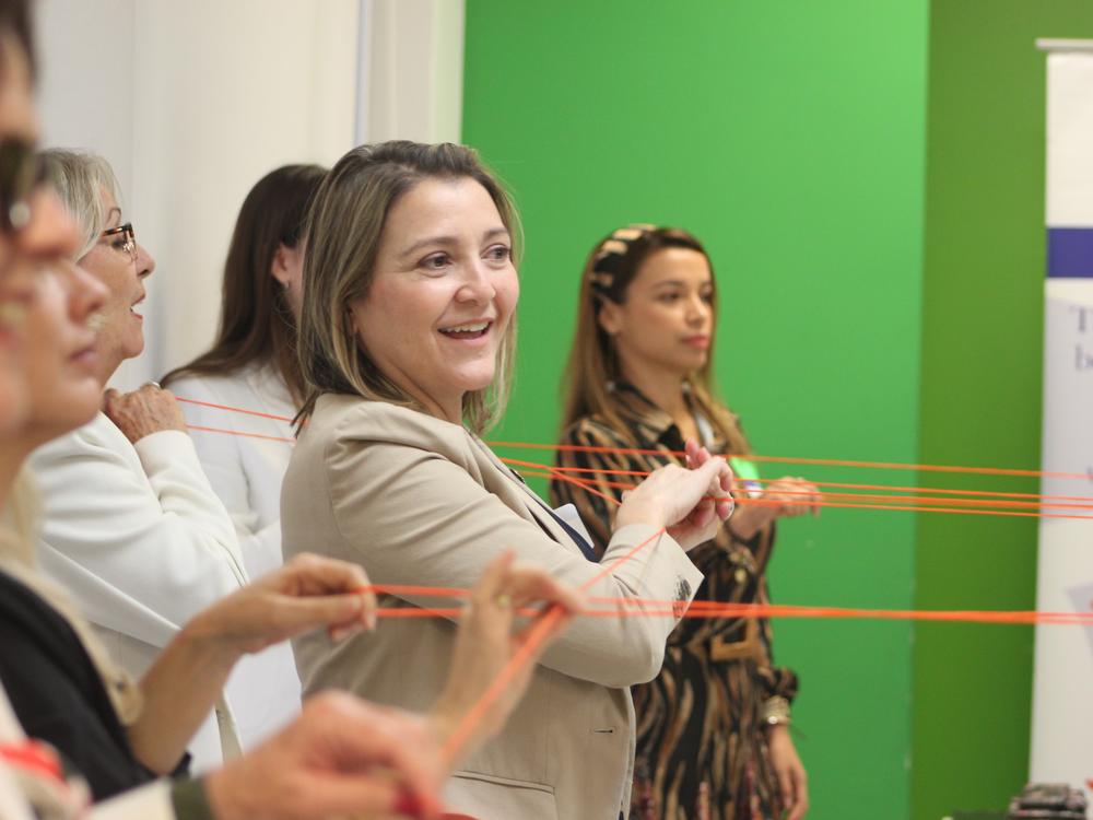 Scarlett Lanzas, second from right, and other information navigators do an exercise in which they use orange string to symbolize how communities are interconnected, at a Nov. 8, 2023, orientation for a pilot project on combating bad information.