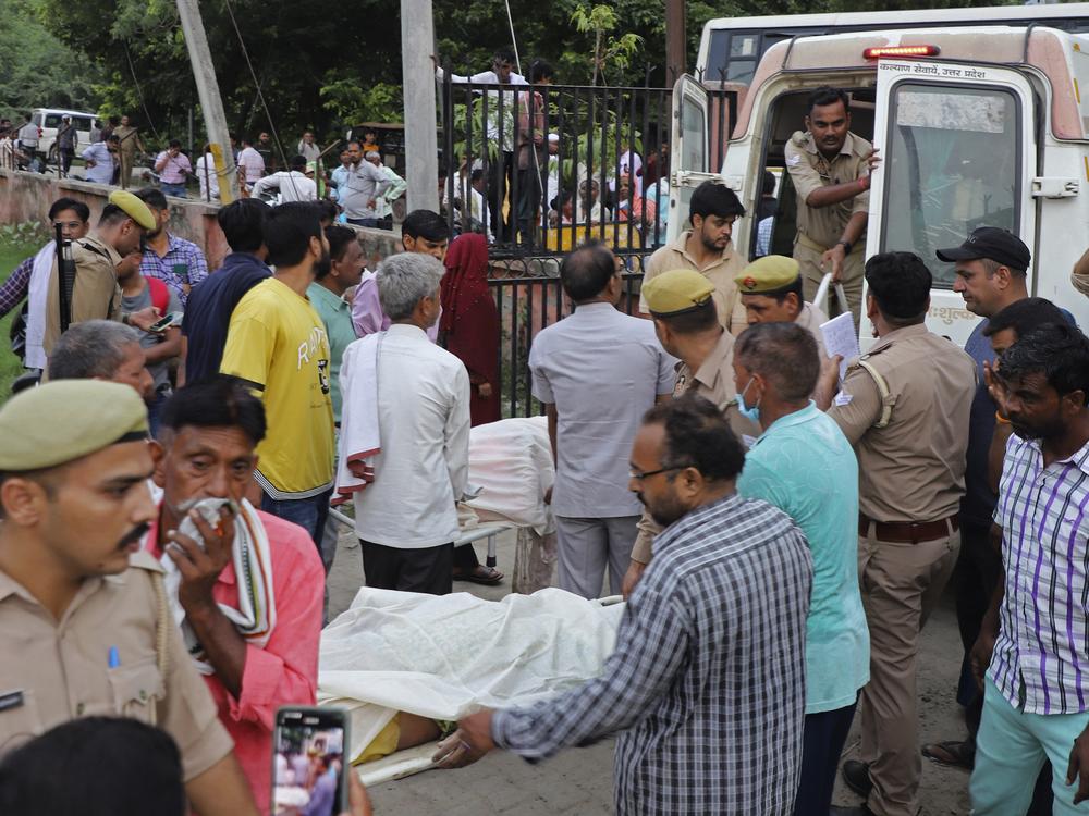Relatives and volunteers carry bodies on stretchers at the Sikandrarao hospital in Hathras district in northern India on Tuesday. A stampede among thousands of people at a religious gathering killed more than 120 and left scores injured, officials said.<br>
