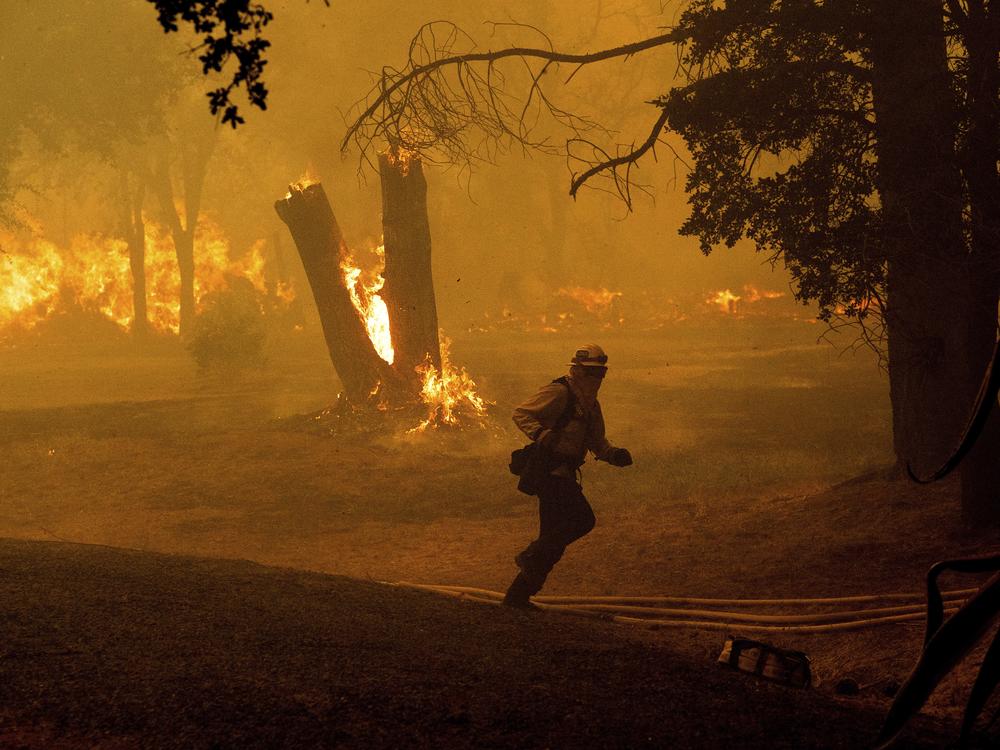 A firefighter runs while battling the Thompson Fire burning in Oroville, Calif., on Tuesday.