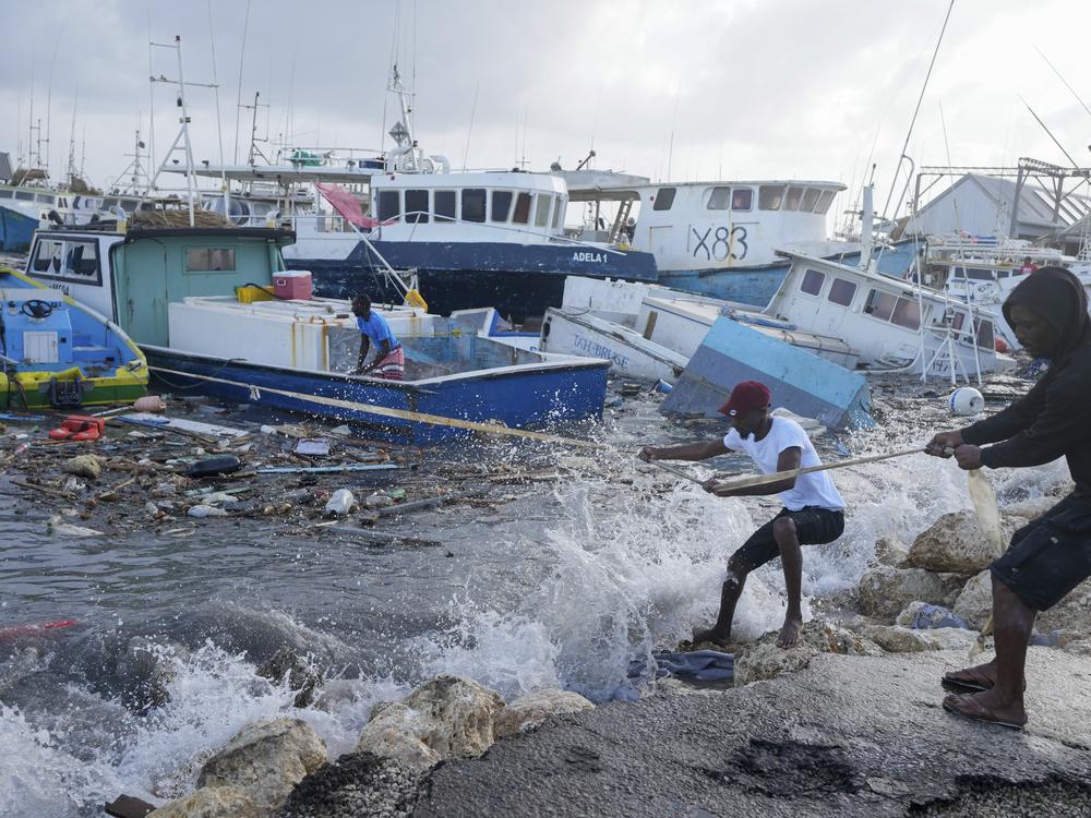 Fishermen pull a boat damaged by Hurricane Beryl back to the dock at the Bridgetown Fisheries in Barbados, Monday, July 1, 2024. 