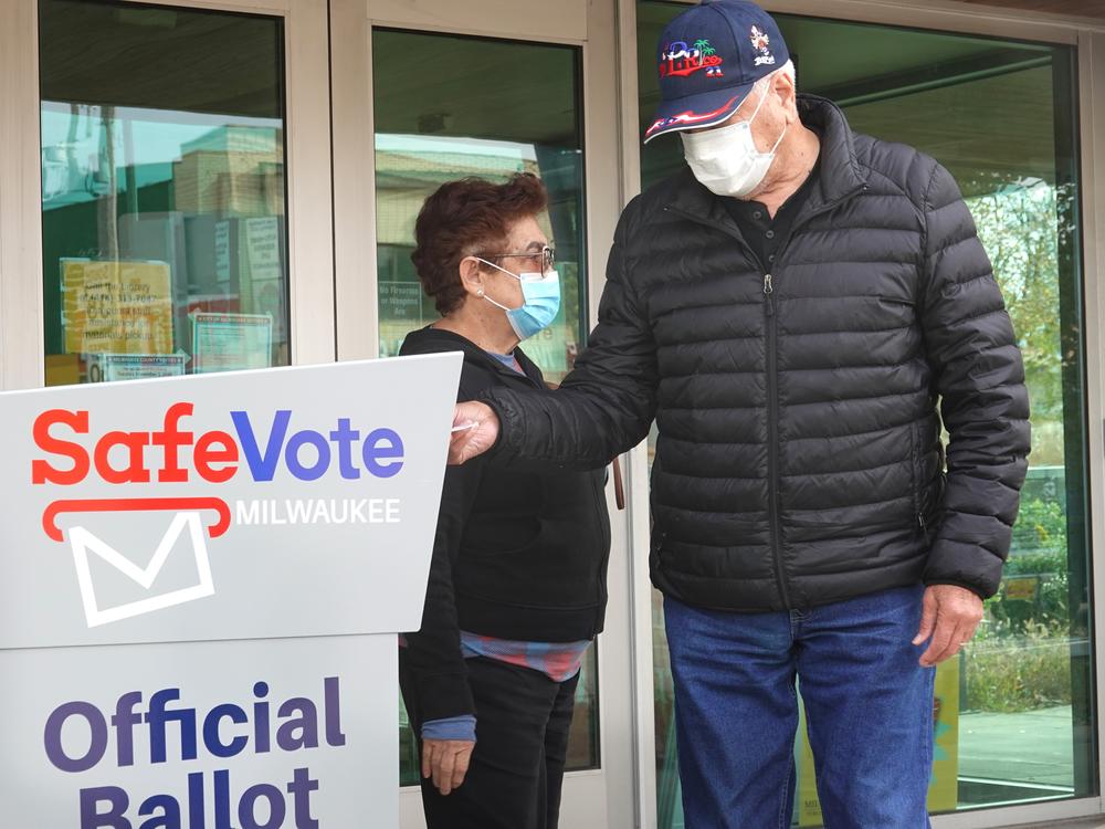 Wisconsin residents deposit mail ballots in a drop box outside of a library in Milwaukee on Oct. 20, 2020.